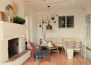 Spanish covered patio lounge with outdoor fireplace, string lights, sectional, and accent chairs